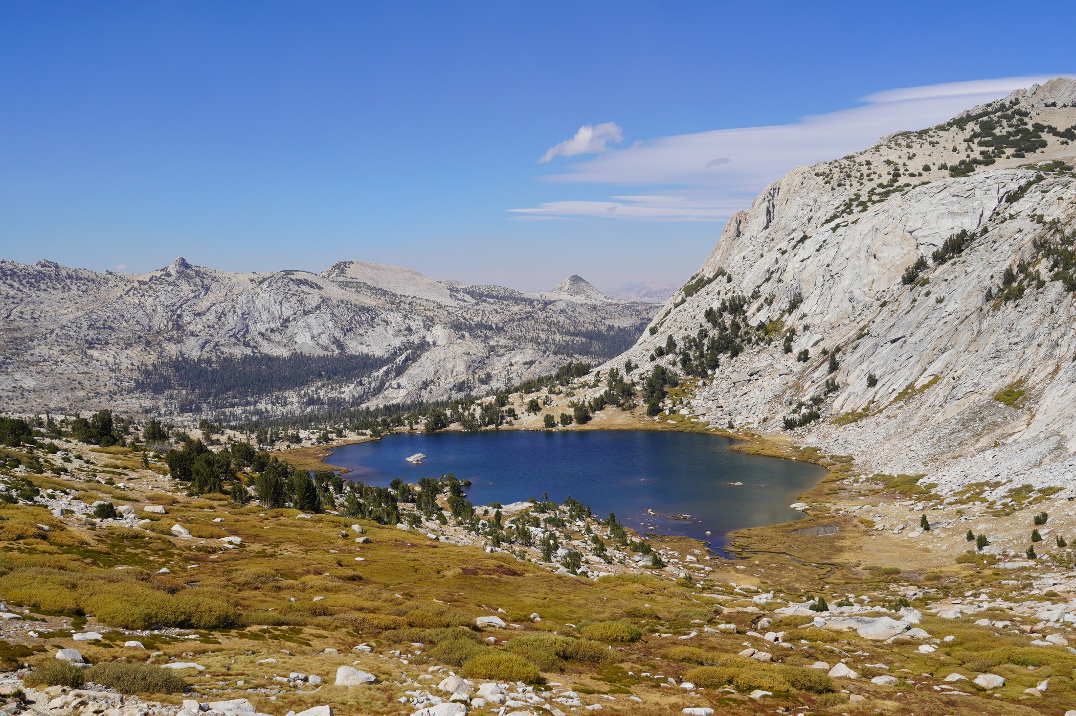 A lake surrounded by granite and autumn meadows